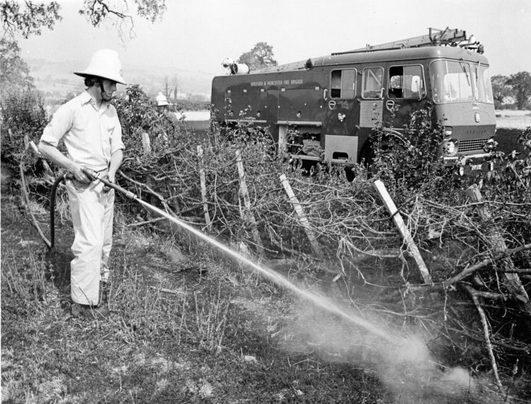 Andy Campbell using a hose reel to damp down following a field fire at Beckford 1976